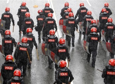 Malaysian riot police officers march on a street under heavy rain during a rally in Kuala Lumpur, Malaysia, Saturday, July 9, 2011.