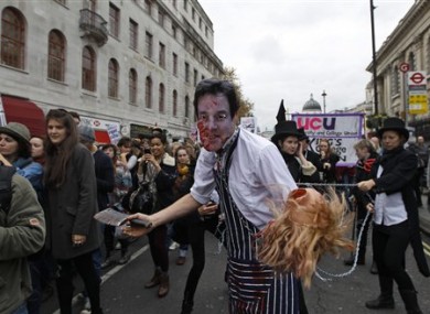 A students waring a mask depicting British Deputy Prime Minister Nick Clegg, pretends to be a butcher, during an anti-cuts student protest in central London, Wednesday, Nov. 9, 2011.