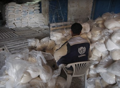 A Palestinian worker sits next to food aid at a United Nations distribution centre in Gaza City (file photo).