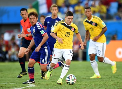 Japan's Toshihiro Aoyama battles for the ball with Colombia's Juan Quinero.